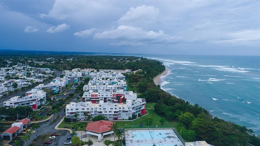 An aerial view shows a coastal apartment complex with a pool and tennis courts — 686 PUERTO NUEVO UNIT 364, VEGA BAJA, PR