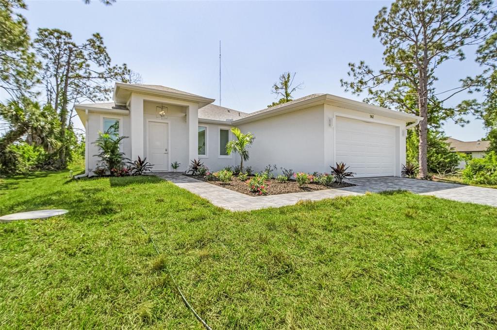 A single-story white house with a paved walkway, attached garage, and landscaped front yard — 162 APOLLO DRIVE, ROTONDA WEST, FL