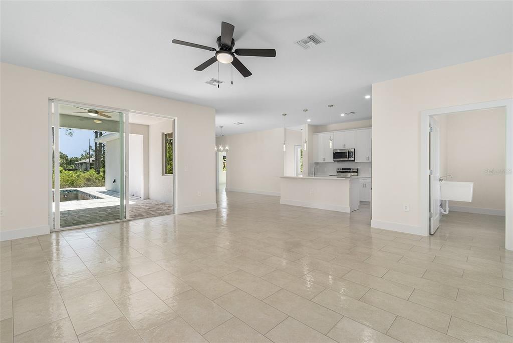 An open-concept living area with light tile floors, a ceiling fan, and a kitchen beyond — 162 APOLLO DRIVE, ROTONDA WEST, FL