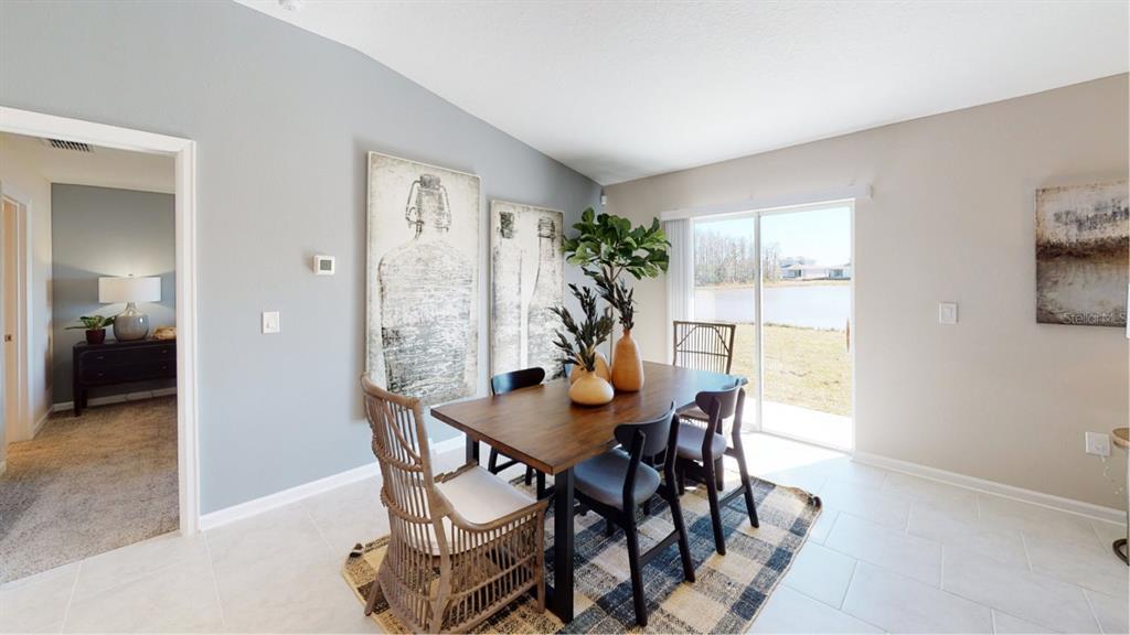 A dining room features a wooden table, mixed seating, wall art, and a sliding glass door — 1631 LOXELY TRAIL, KISSIMMEE, FL