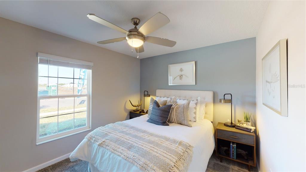 A bedroom features a bed with a blue accent wall, a ceiling fan, and windows — 1631 LOXELY TRAIL, KISSIMMEE, FL