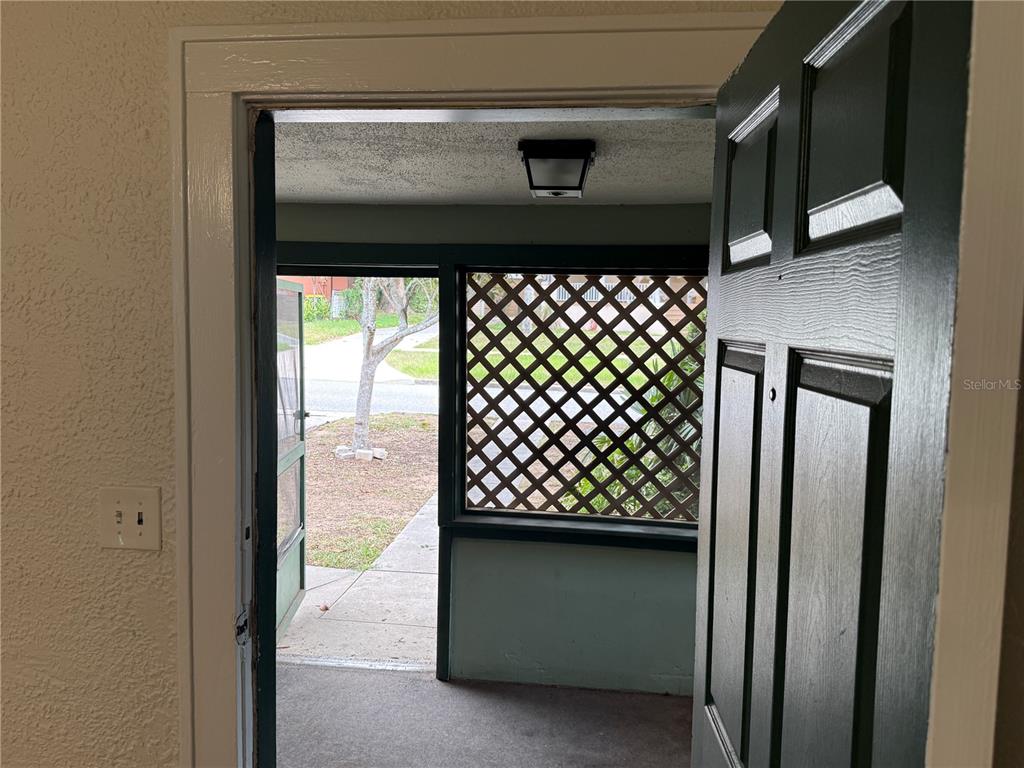An open door reveals a covered porch with lattice walls and a concrete floor — 534 W OSCEOLA STREET, CLERMONT, FL