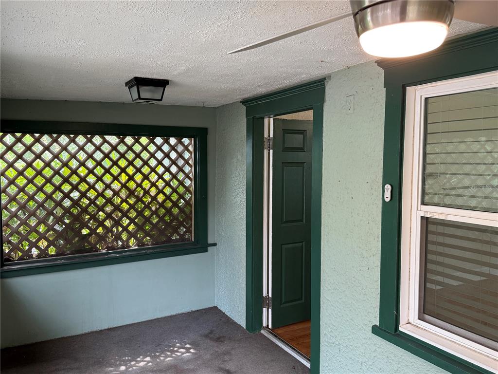 A covered porch features a green door, lattice window screen, and a ceiling fan — 534 W OSCEOLA STREET, CLERMONT, FL