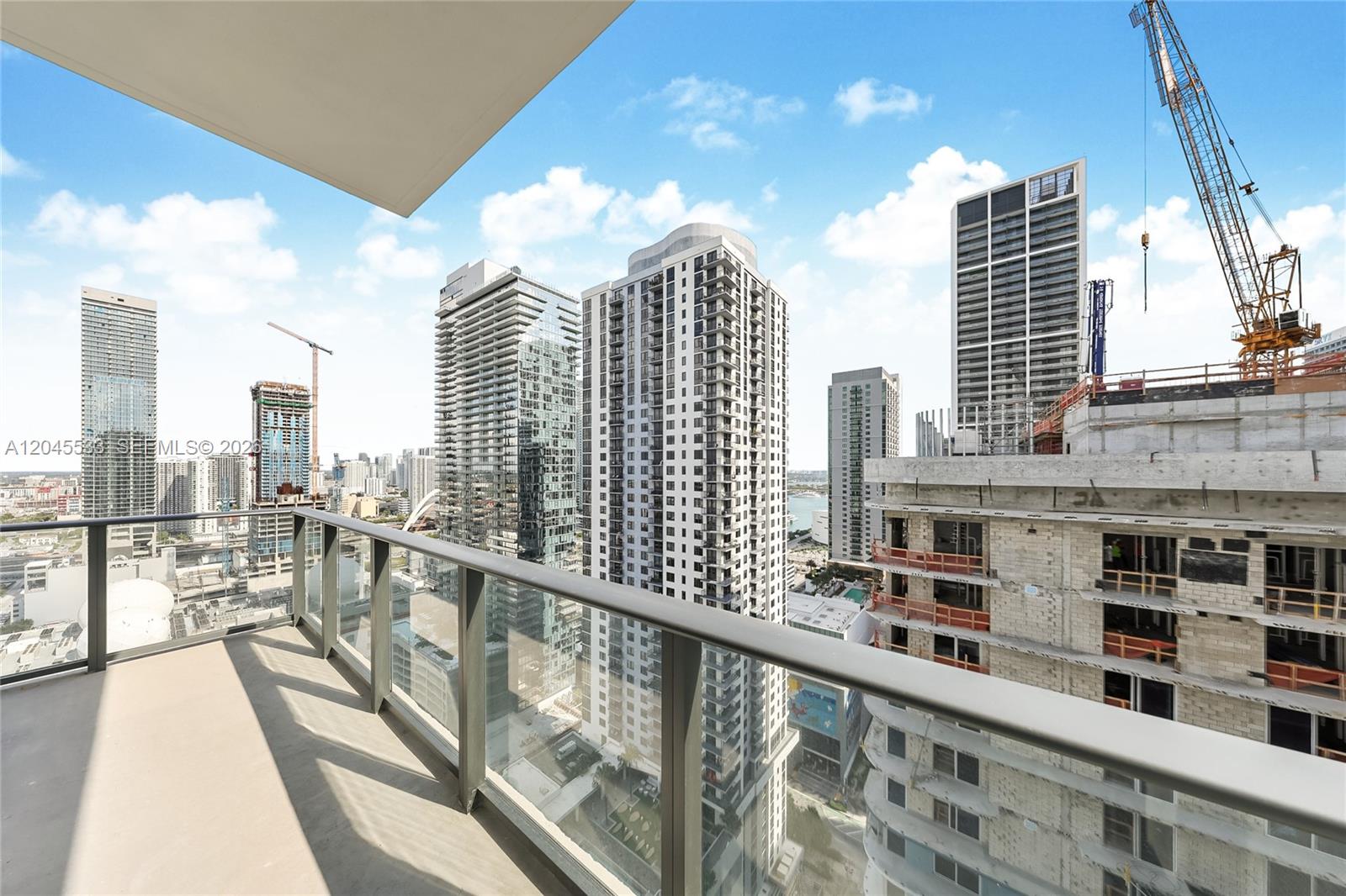 A balcony overlooks a dense urban skyline featuring several high-rise buildings and active construction sites — 11 NE 6th St # 3209, Miami FL 33132, MIAMI, FL
