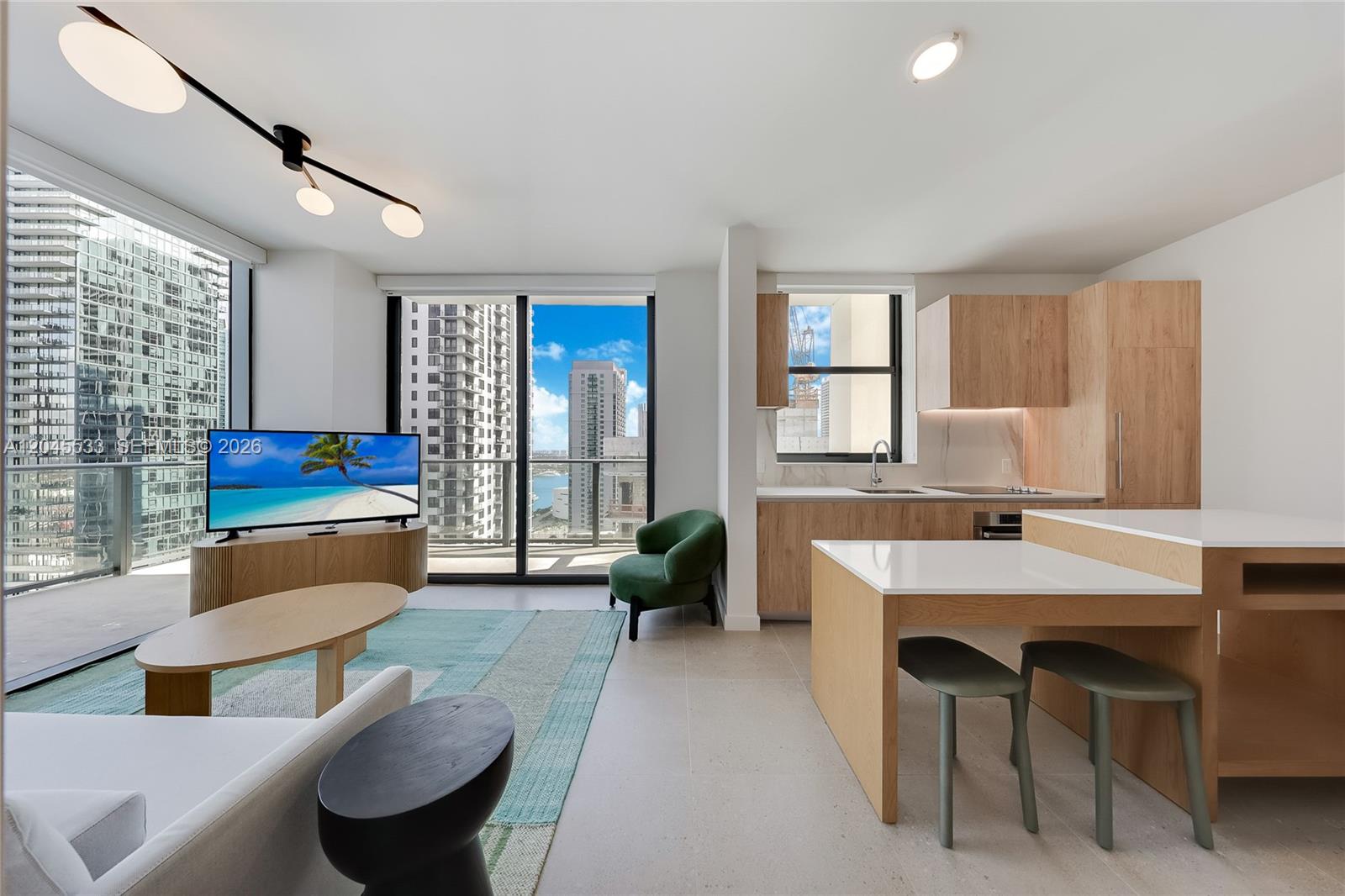 A modern apartment living area features a kitchen, dining island, and balcony with city views — 11 NE 6th St # 3209, Miami FL 33132, MIAMI, FL