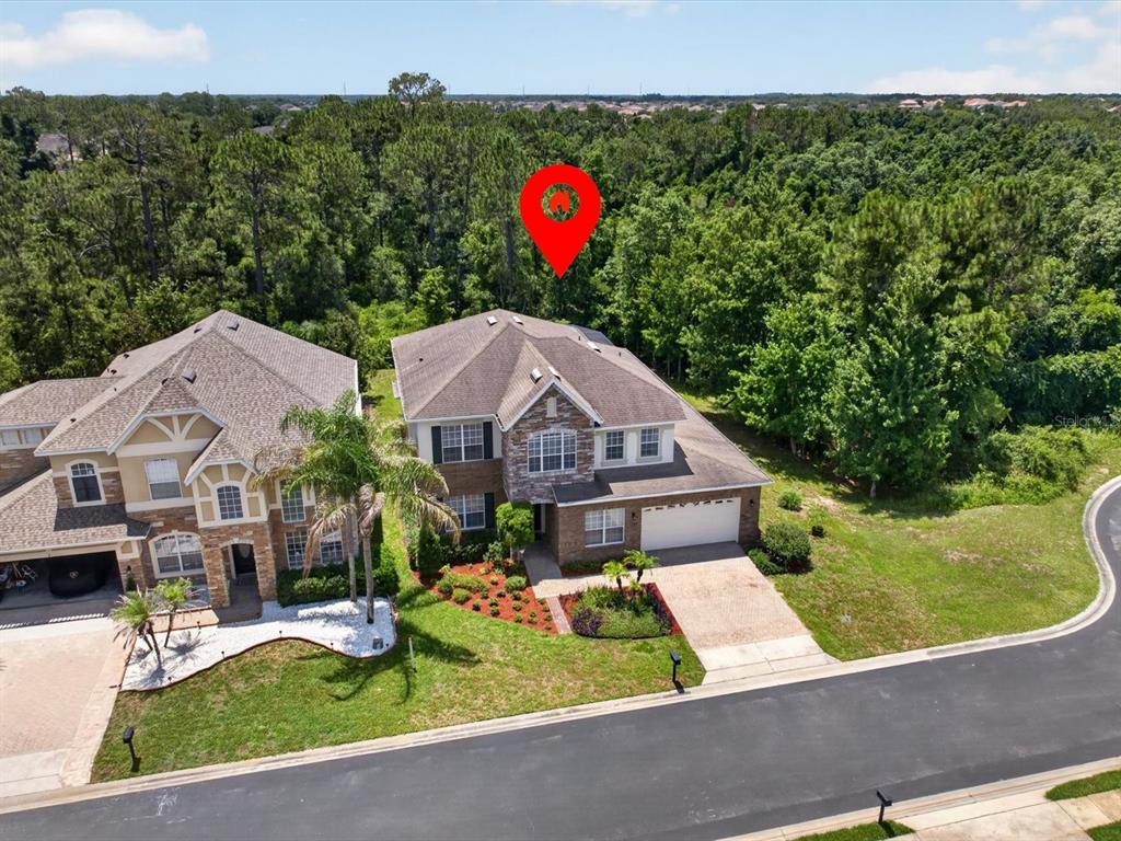 An aerial view shows two suburban houses with shingled roofs surrounded by dense green trees — 561 HARRISWOOD COURT, DAVENPORT, FL