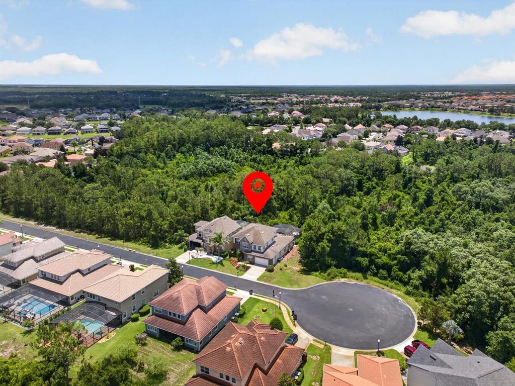 An aerial view shows a suburban house with a red pin in a cul-de-sac — 561 HARRISWOOD COURT, DAVENPORT, FL