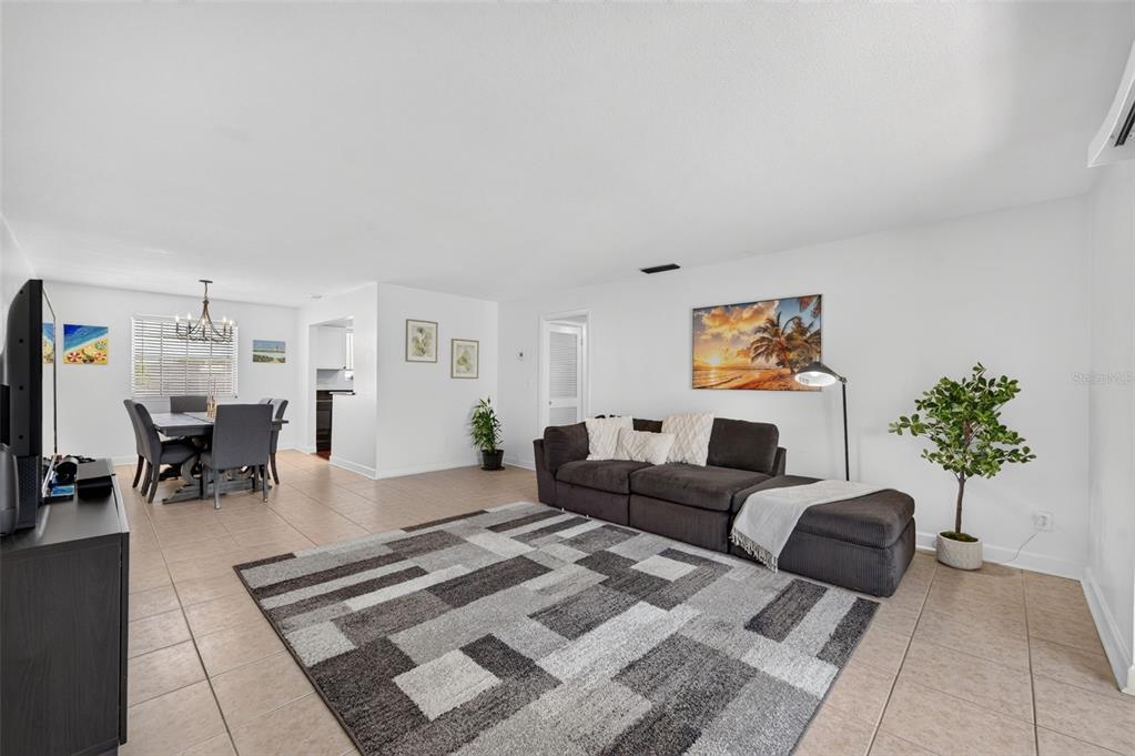 A living room and dining area with tile floors, a dark sofa, and a rug — 1500 GAY ROAD UNIT 3C, WINTER PARK, FL