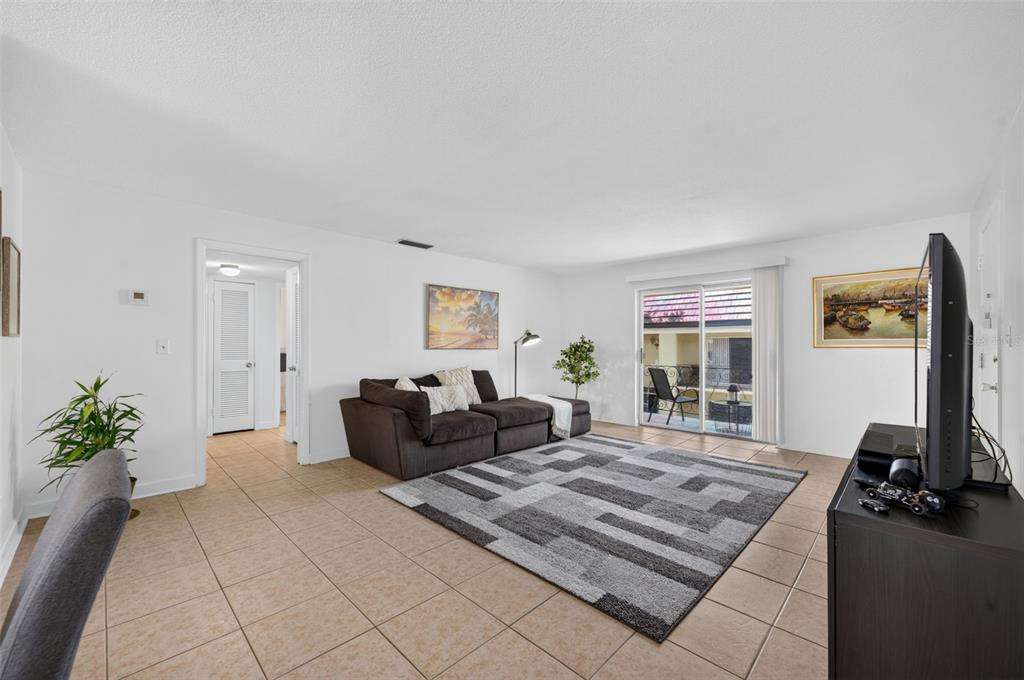 A living room with tile flooring, a dark sectional sofa, and a sliding glass door — 1500 GAY ROAD UNIT 3C, WINTER PARK, FL