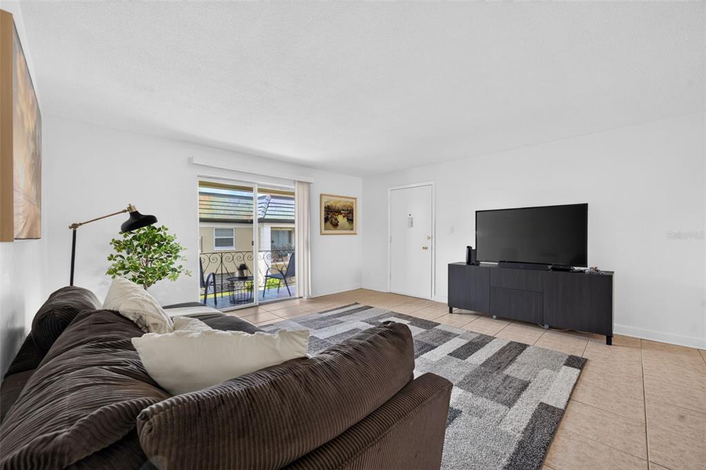A living room features a brown sofa, a television on a console, and a sliding door — 1500 GAY ROAD UNIT 3C, WINTER PARK, FL