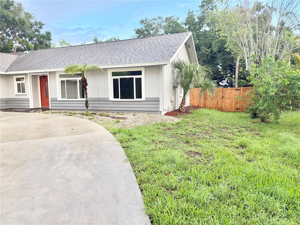 A single-story house with gray siding, a red front door, and a concrete driveway — 5274 CEDAR HAMMOCK COURT, SARASOTA, FL