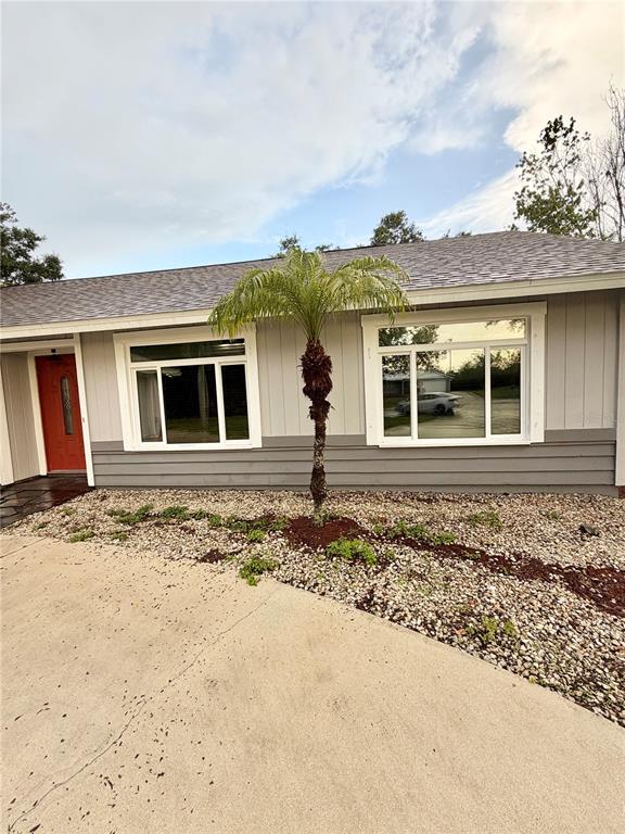 The exterior of a gray house features a palm tree, a red door, and two large windows — 5274 CEDAR HAMMOCK COURT, SARASOTA, FL