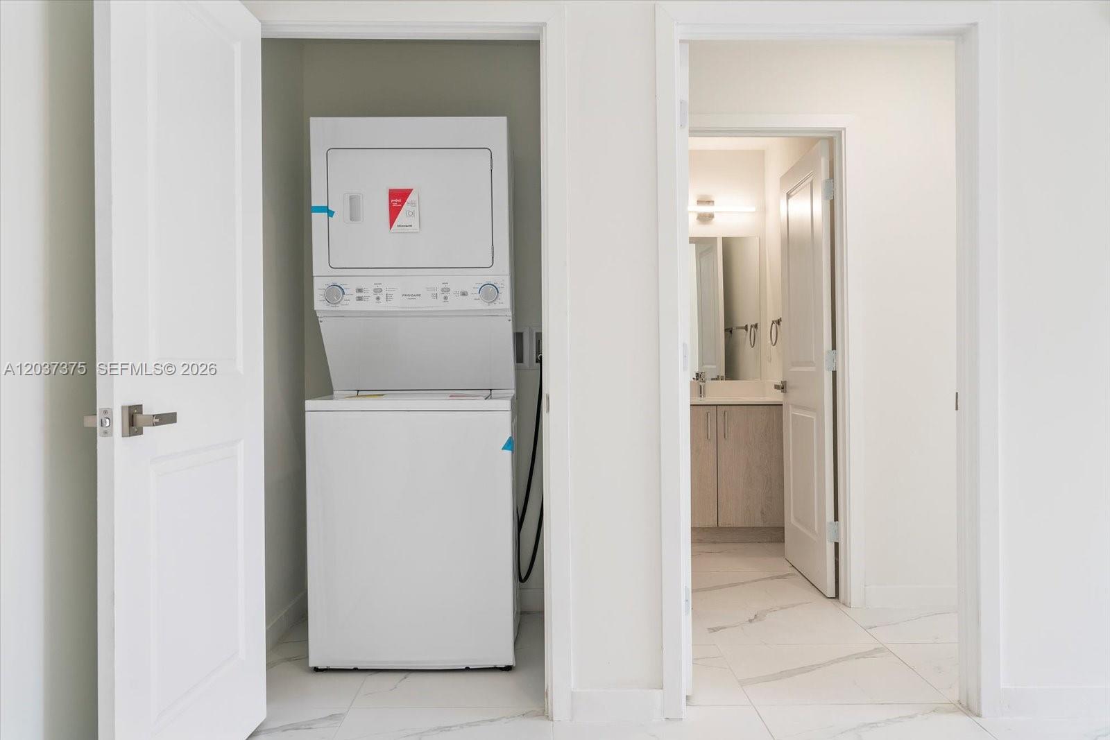 A laundry closet with a stacked washer and dryer sits beside a bathroom doorway — 420 SW 7th Ave # 201, Miami FL 33130, MIAMI, FL