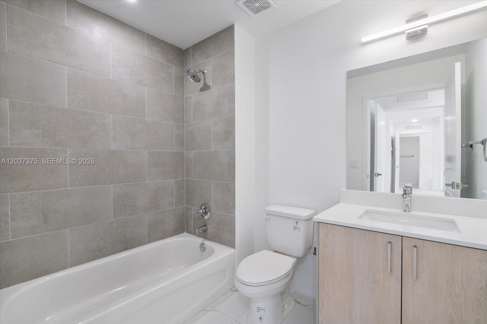 A bathroom features a bathtub with gray tile walls, a white toilet, and a wood vanity — 420 SW 7th Ave # 201, Miami FL 33130, MIAMI, FL