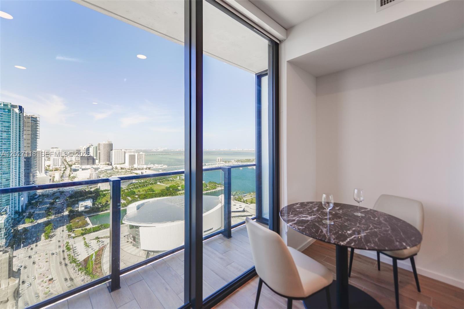 A dining area with a marble table and chairs overlooks a balcony and city skyline — 398 NE 5th St # 3505, Miami FL 33132, MIAMI, FL