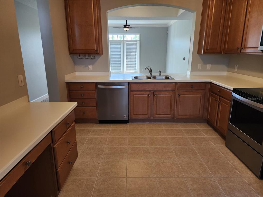 A kitchen features wood cabinets, stainless steel appliances, and light-colored countertops over tile flooring — 1211 STONECUTTER DRIVE UNIT 403, CELEBRATION, FL