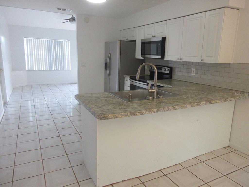 A kitchen with white cabinets, stainless steel appliances, and a granite-topped island with a sink — 14131 SW 30TH TERRACE ROAD, OCALA, FL