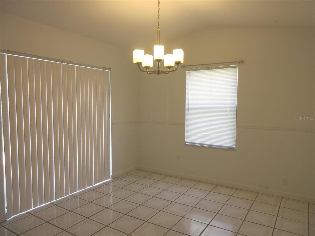 A dining area features white walls, tile flooring, a chandelier, and a sliding glass door — 14131 SW 30TH TERRACE ROAD, OCALA, FL