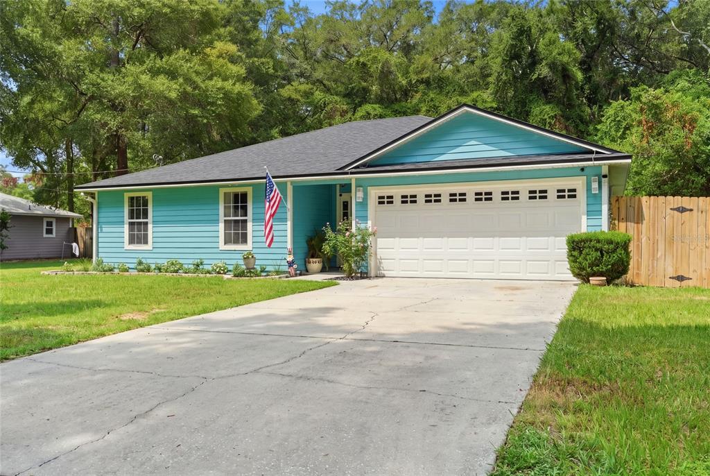 A teal, single-story house with a white garage door and a concrete driveway — 17686 NW 239TH TERRACE, HIGH SPRINGS, FL
