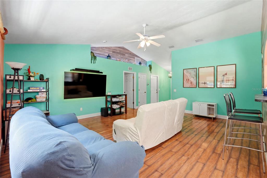 A living room features mint green walls, wood-look flooring, a vaulted ceiling, and two sofas — 17686 NW 239TH TERRACE, HIGH SPRINGS, FL