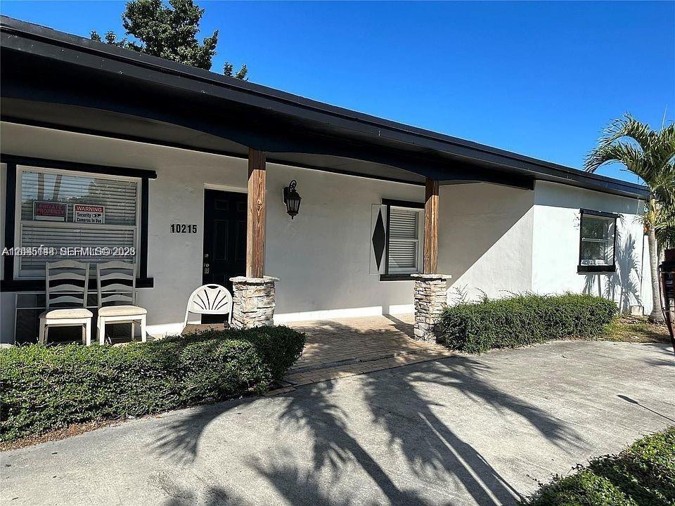 A single-story house exterior features a covered porch, stone columns, and a concrete driveway — 10215 SW 171st St, Miami FL 33157, MIAMI, FL