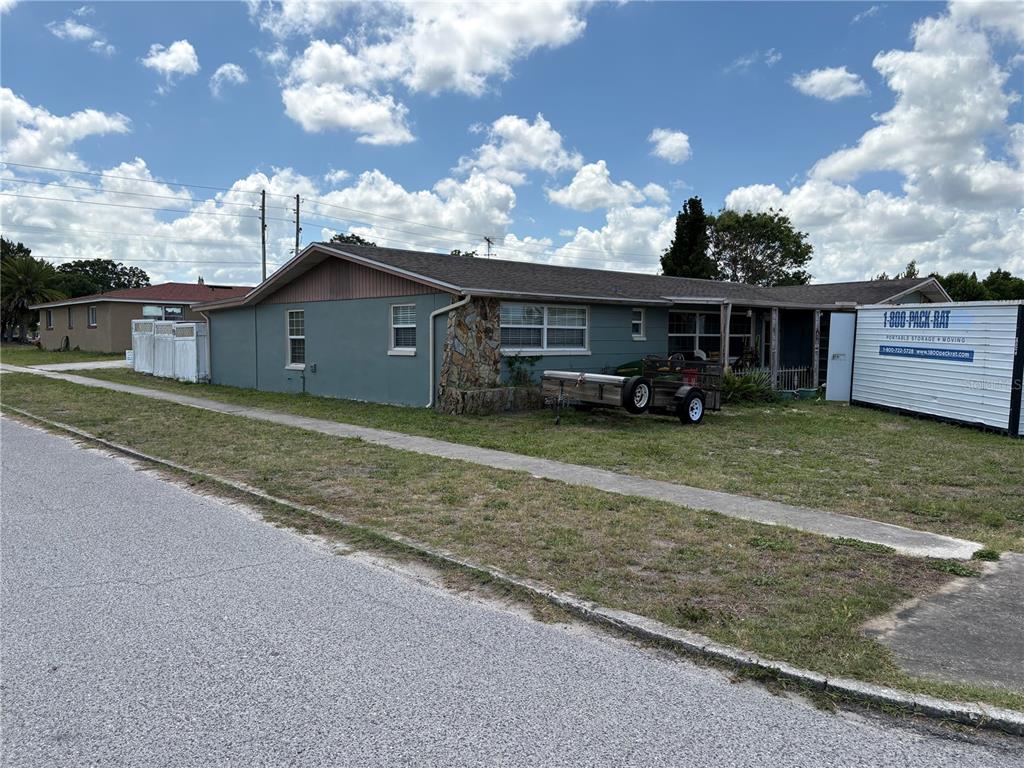 A side view of a single-story house with a white fence and a sidewalk — 4934 DAPHNE STREET, NEW PORT RICHEY, FL