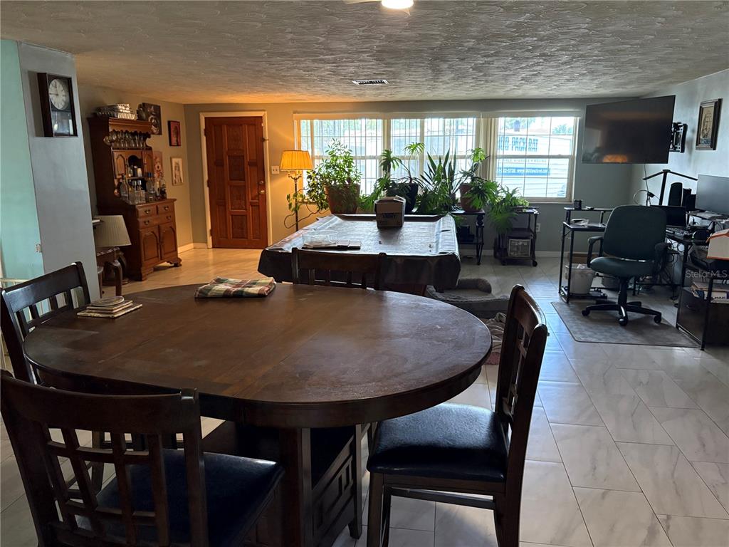 A spacious living room features light gray walls, white tiled floors, and a textured ceiling — 4934 DAPHNE STREET, NEW PORT RICHEY, FL