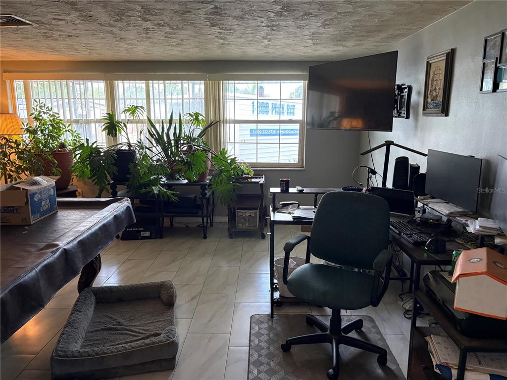 A spacious room with light gray walls, white tile flooring, and a wooden bookshelf — 4934 DAPHNE STREET, NEW PORT RICHEY, FL