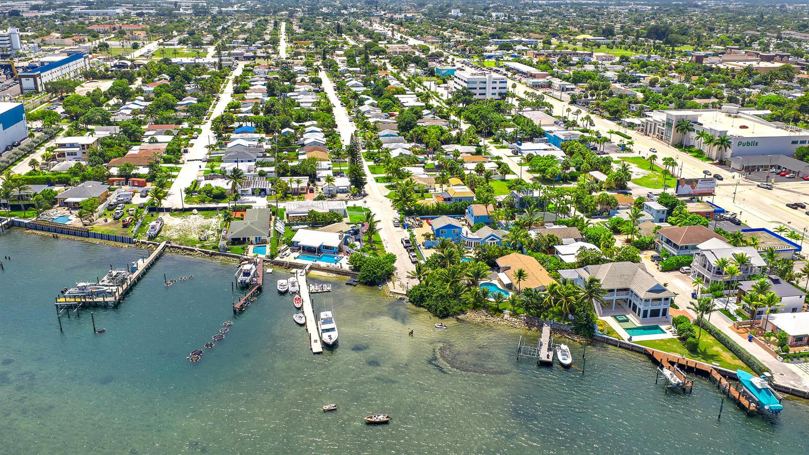 An aerial view shows waterfront homes with private docks and pools along a coastal neighborhood — 176 E 24th Street, Riviera Beach FL 33404, RIVIERA BEACH, FL