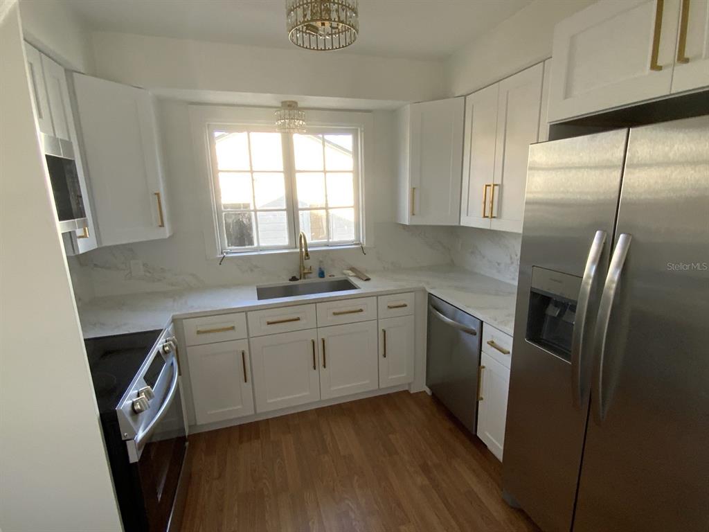 A kitchen features white cabinets, stainless steel appliances, a sink, and light-colored countertops — 608 HIGHLAND AVENUE, ORLANDO, FL
