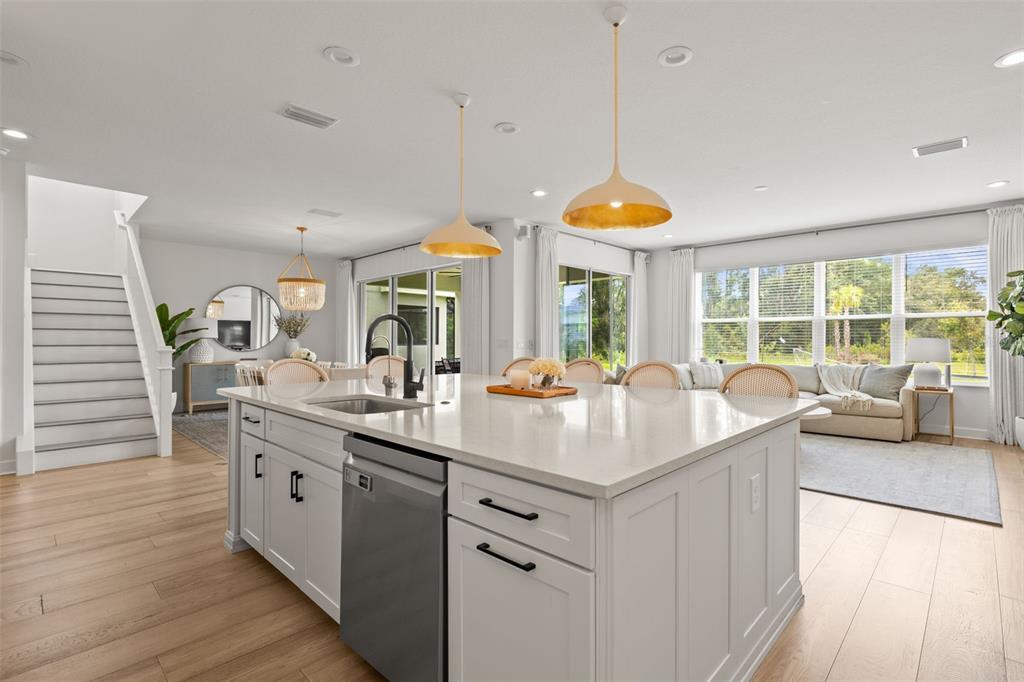 A kitchen island with a stainless steel dishwasher sits in an open-concept living space — 3541 GREAT BANYAN WAY, WESLEY CHAPEL, FL