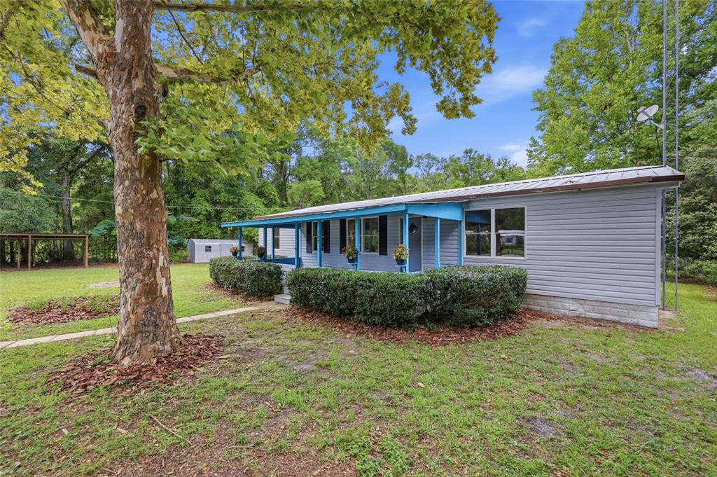 A single-story house with light blue siding, a metal roof, and a covered front porch — 187 SW PEACH GLEN, HIGH SPRINGS, FL