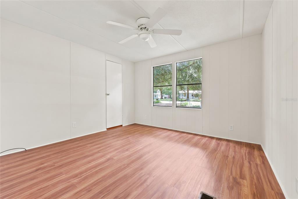 An empty bedroom with white paneled walls, wood-look flooring, and a ceiling fan — 187 SW PEACH GLEN, HIGH SPRINGS, FL