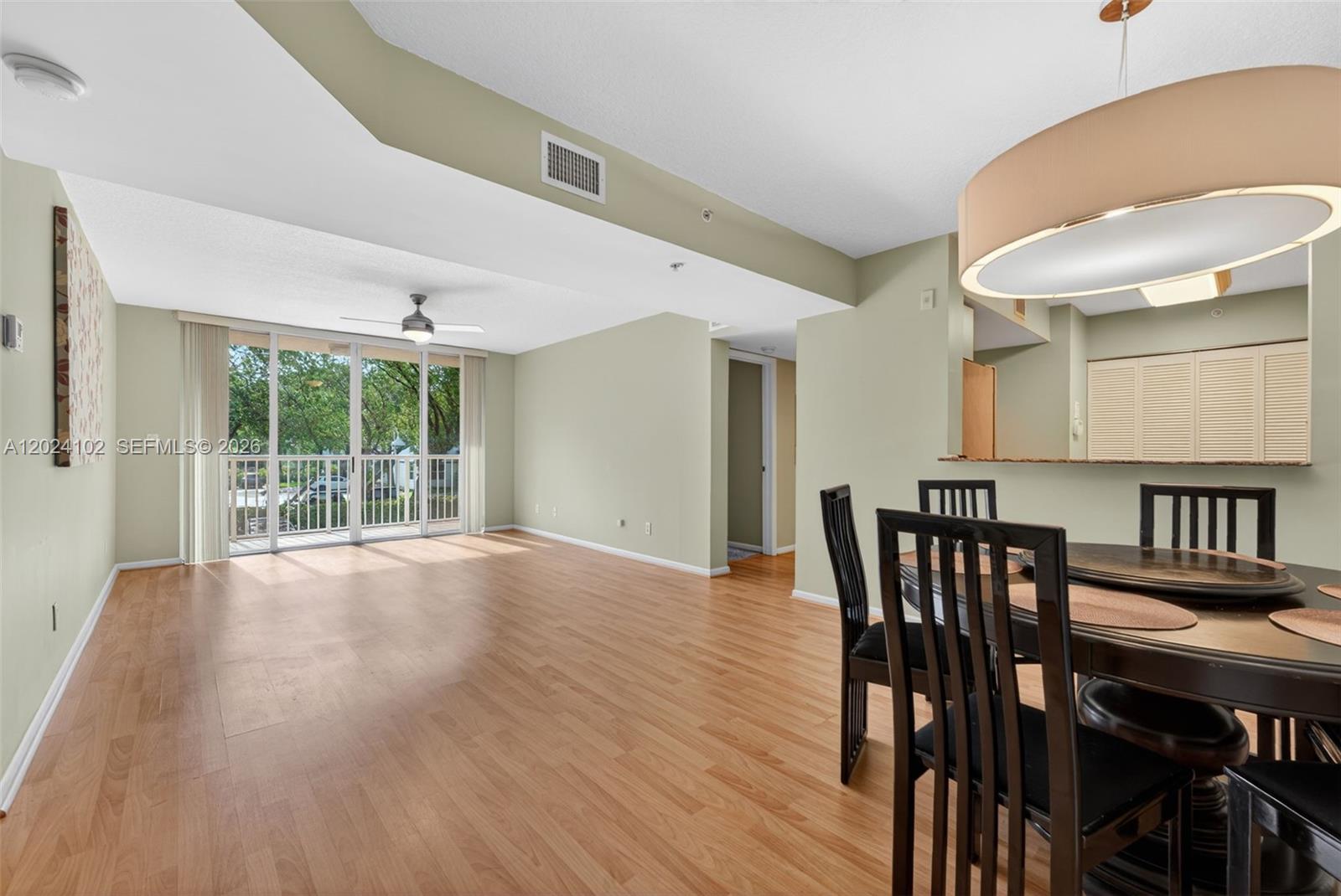 A dining area and living room feature light wood flooring and a sliding glass door — 619 E Sheridan St # 203, Dania Beach FL 33004, DANIA BEACH, FL