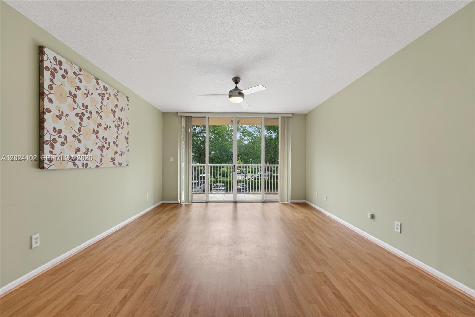 An empty room with light green walls, wood-look flooring, a ceiling fan, and sliding glass doors — 619 E Sheridan St # 203, Dania Beach FL 33004, DANIA BEACH, FL