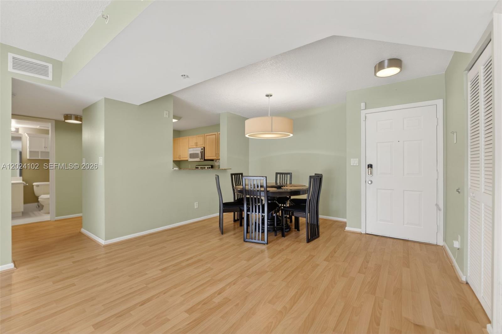 A dining area with a round table and chairs sits adjacent to a kitchen pass-through — 619 E Sheridan St # 203, Dania Beach FL 33004, DANIA BEACH, FL