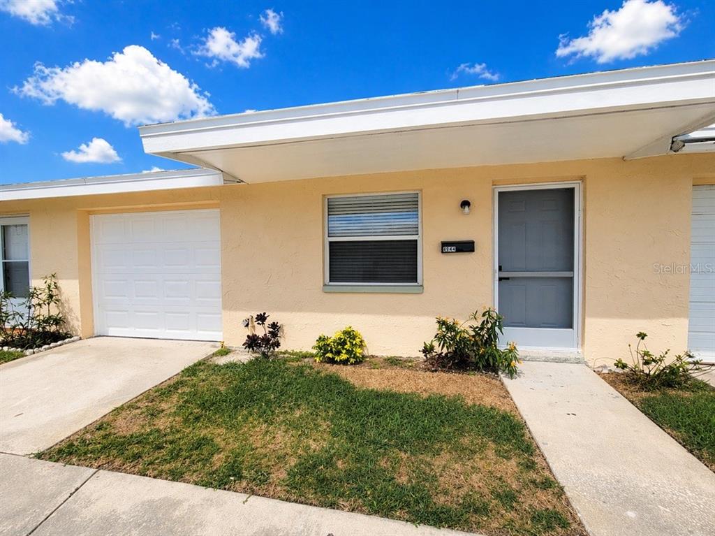 A single-story house with a beige exterior, a white garage door, and a front walkway — 4944 ELKNER STREET, NEW PORT RICHEY, FL