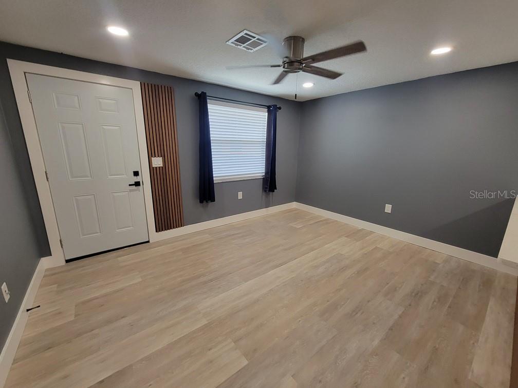 A room with gray walls, wood-look flooring, a ceiling fan, and a white door — 4944 ELKNER STREET, NEW PORT RICHEY, FL