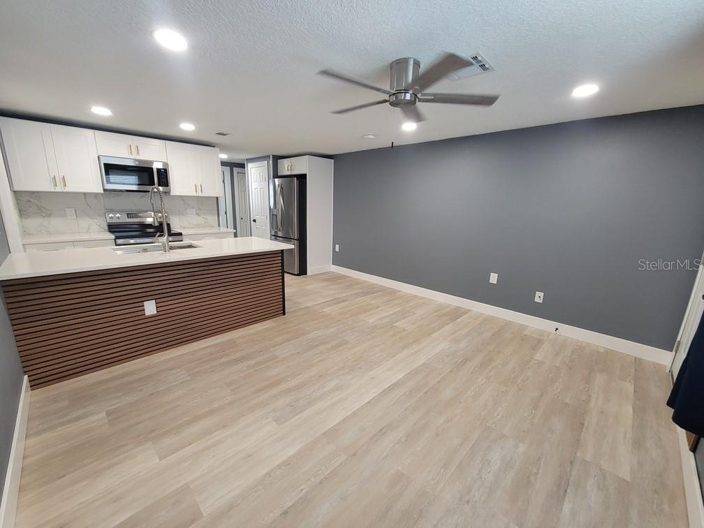 A kitchen with white cabinets, a slatted island, and a large gray accent wall — 4944 ELKNER STREET, NEW PORT RICHEY, FL