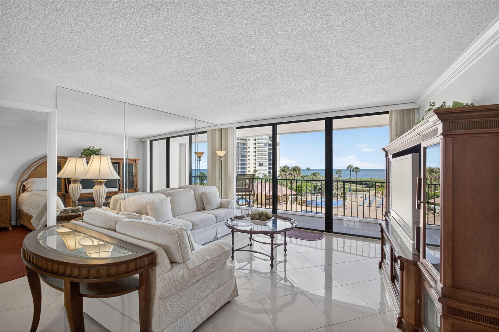 A living room with tile floors, a mirrored wall, and a balcony overlooking the ocean — 100 Ocean Trail Way # 305, Jupiter FL 33477, JUPITER, FL