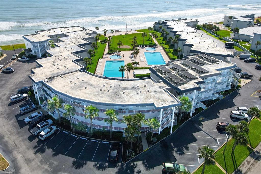 An aerial view shows a multi-story beachfront resort complex with two swimming pools and parking — 4841 SAXON DRIVE UNIT E206, NEW SMYRNA BEACH, FL