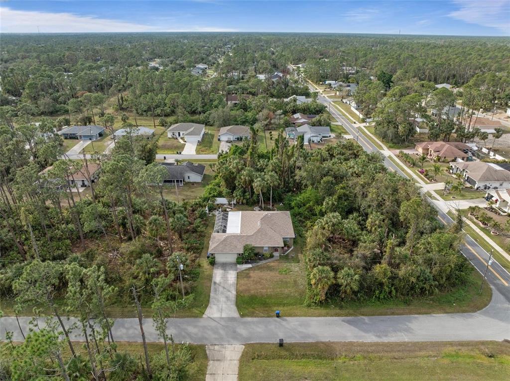 An aerial view shows a single-story house with a pool cage surrounded by wooded lots — 3953 VEHLIN STREET, NORTH PORT, FL