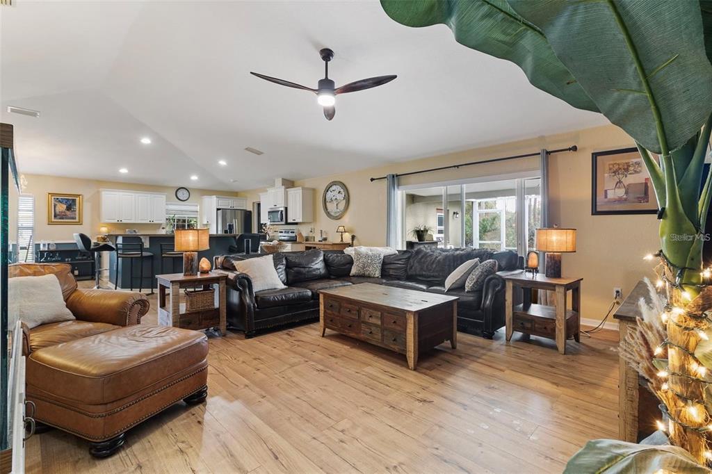 A living room with wood floors, a leather sectional, and an open-concept kitchen — 3953 VEHLIN STREET, NORTH PORT, FL