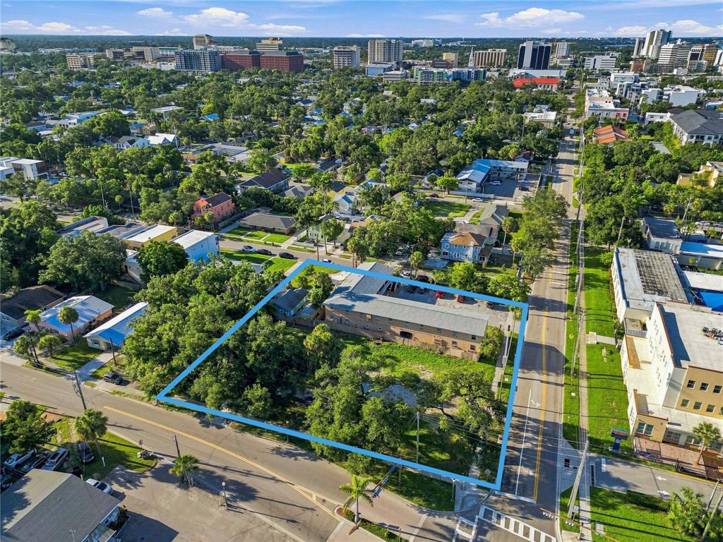 An aerial view shows a vacant, grass-covered lot bordered by a street and a building — 918 ORANGE AVENUE, SARASOTA, FL
