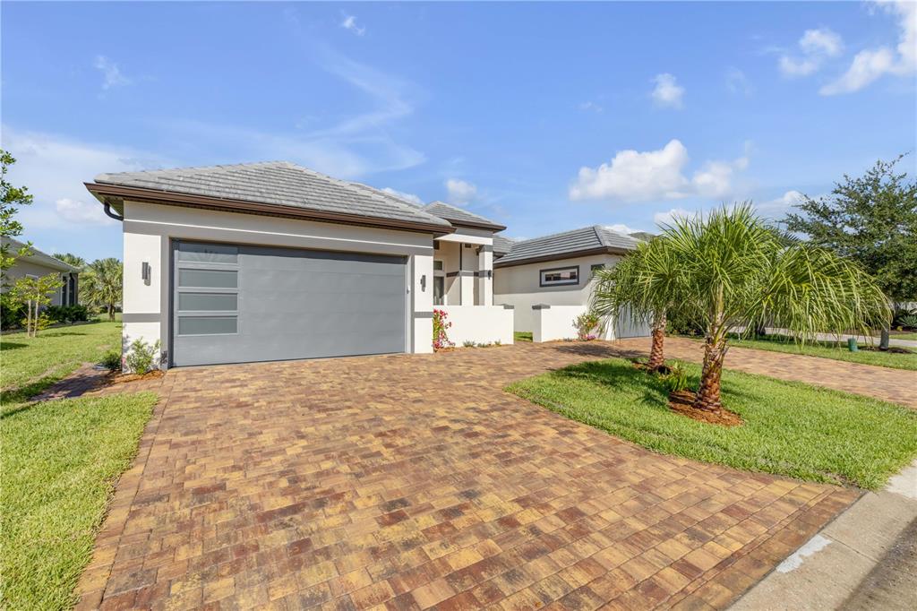A single-story house with a gray garage door and a brick paver driveway — 116 LONGVIEW WAY N, PALM COAST, FL