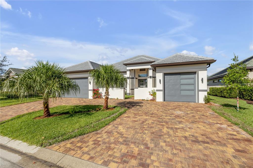 A single-story house with a paver driveway, two garage doors, and two small palm trees — 116 LONGVIEW WAY N, PALM COAST, FL