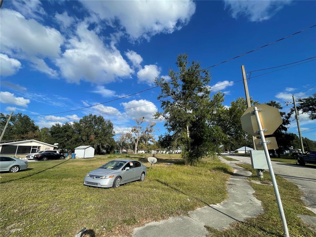 A silver sedan is parked on a grassy lot next to a sidewalk and trees — 7 4TH STREET SE, FORT MEADE, FL