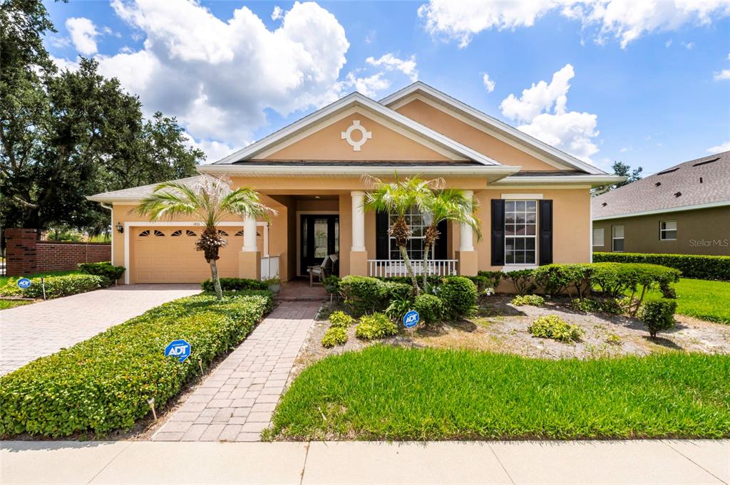 A single-story house with a tan exterior, a two-car garage, and a paved walkway — 1801 BURDOCK DRIVE, WINTER GARDEN, FL