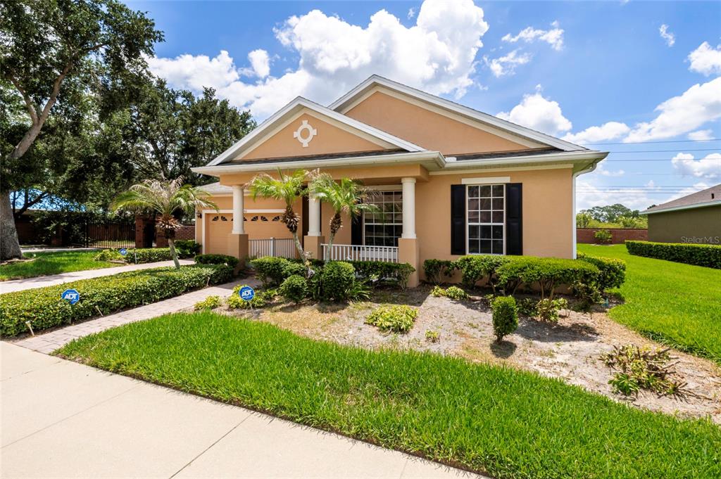 A single-story tan house with a front porch, palm trees, and a manicured lawn — 1801 BURDOCK DRIVE, WINTER GARDEN, FL