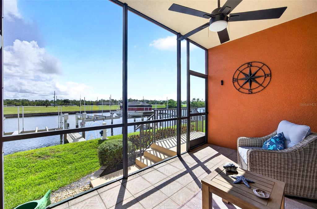 A screened-in patio features tiled flooring, a ceiling fan, and a view of a canal — 3500 MONDOVI COURT UNIT 1011, PUNTA GORDA, FL